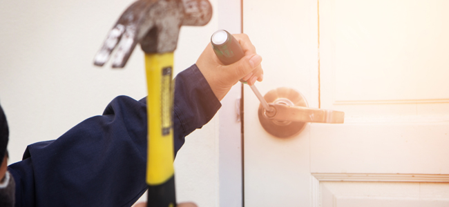 Burglar trying to break into a house with a hammer and