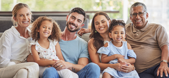 Interracial family, happy portrait and parents on the living room sofa with children, relax in lounge together and smile on the couch. Kids, mother and father with love for senior people in house