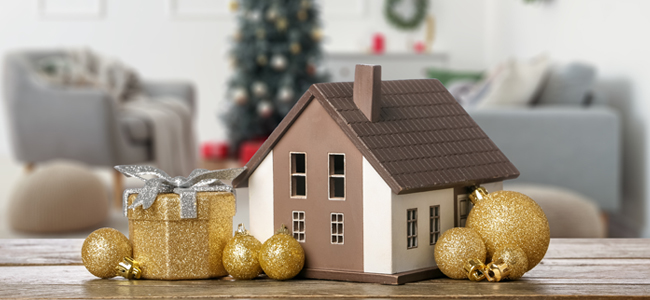 Model of house with Christmas gift and decorations on table in r