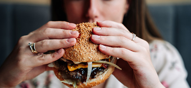 Fast food burger eat. Pretty Young Happy Woman Eating Tasty Hamburger. Junk Food Concept.